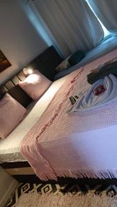 un letto con coperta rosa e cuscini sopra di Loft das Esrelas c/Ar p/4 a Volta Redonda Altre 24 foto