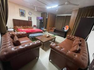 ein Wohnzimmer mit Ledermöbeln und einem Bett in der Unterkunft Secure Private Apartment Privacy Guaranteed in Lahore + 2 Fotos