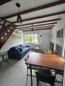 ein Wohnzimmer mit einem Tisch und einem blauen Sofa in der Unterkunft Apartamento Charmoso com Mezanino em Juquehy in São Sebastião