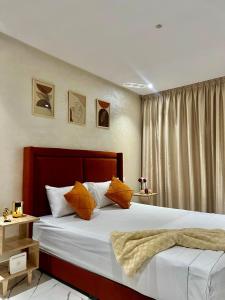 una camera da letto con un letto con lenzuola bianche e cuscini arancioni di Studio Glamour a Casablanca