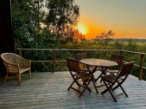 a table and chairs on a wooden deck with a sunset at A-Frame Houses Overlooking Öland's Landscape in Mörbylånga +11 photos