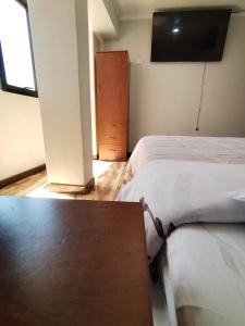 two beds in a room with a table and a tv at La Merced in Juliaca