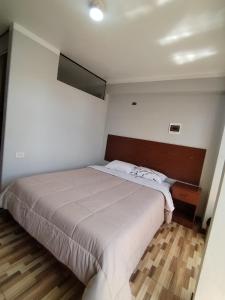 a bedroom with a large bed with a wooden headboard at La Merced in Juliaca
