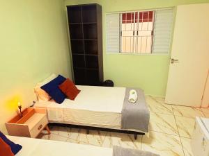 una piccola camera da letto con un letto e una finestra di Golden Garden Hostel a Ubatuba