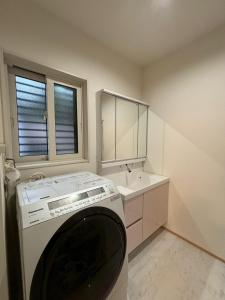 a washing machine in a bathroom with a sink at Riverside Garden -kumanokodo-chikatsuyu- in Tanabe