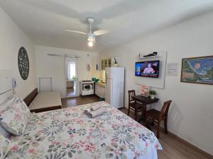 a bedroom with a bed and a kitchen with a refrigerator at Flat Privativo Rua das Pedras in Búzios