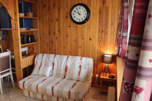 a living room with a couch and a clock on the wall at Cosylocation Super Besse in Besse-et-Saint-Anastaise