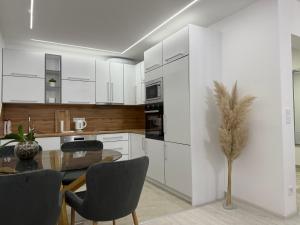 a kitchen with white cabinets and a table and chairs at Apartman welsh in Bugojno