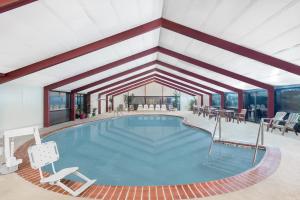 een zwembad in een kamer met stoelen en tafels bij Howard Johnson by Wyndham Saugerties in Saugerties