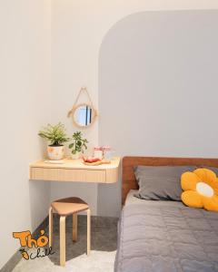 een slaapkamer met een bed, een tafel en een bureau bij Thỏ Chill Homestay in Vung Tau