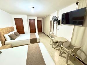 a hotel room with a bed and a table and a tv at Hotel Pereira Central in Pereira