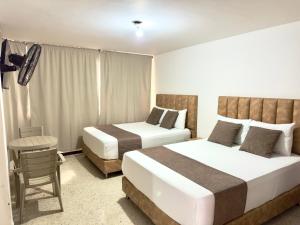 a hotel room with two beds and a table at Hotel Pereira Central in Pereira