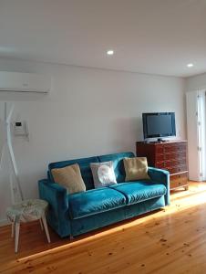 a living room with a blue couch and a tv at Dolce Vita Heroismo in Porto