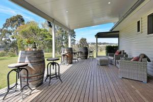 a covered deck with chairs and tables and a grill at Glandore Estate in Pokolbin