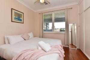 a white bed in a room with a window at Glandore Estate in Pokolbin