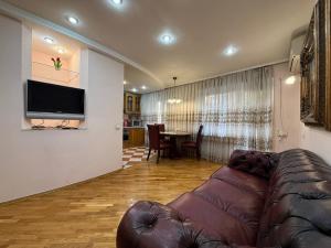 ein Wohnzimmer mit einer Ledercouch und einem Tisch in der Unterkunft Воскресенская 12- 2 кв Евро Центр in Dnipro + 15 Fotos