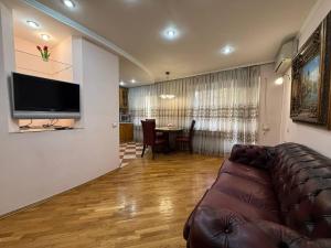 ein Wohnzimmer mit einem braunen Sofa und einem Tisch in der Unterkunft Воскресенская 12- 2 кв Евро Центр in Dnipro