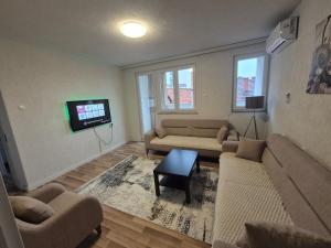 a living room with couches and a flat screen tv at Nice apartment at the center of Vushtrri city in Mitrovicë +3 photos