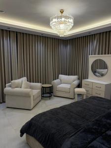 una camera da letto con un letto, due sedie e un lampadario di جوهرة العزيزية a Dhahran