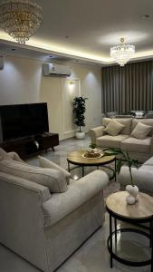 un soggiorno con divani, tavoli e TV di جوهرة العزيزية a Dhahran