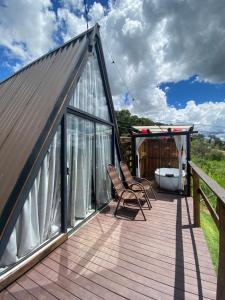 Una terraza con dos sillas y una bañera en una casa. en Chalé Alto da Montanha, en Socorro