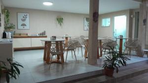 a dining room with tables and chairs and a kitchen at Canoa dos Anjos Suites in Arraial do Cabo