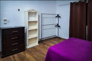 a bedroom with a purple bed and a dresser at La casa azul en Ticul Yucatán in Ticul