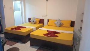 two beds in a small room with yellow sheets at Lilly Rooms in Kandy