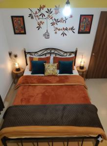 ein Schlafzimmer mit einem Bett mit orangefarbenen Laken und blauen Kissen in der Unterkunft MalangFehmi Goa Escape in Arambol