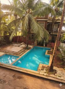ein Swimmingpool mit einer Palme vor einem Haus in der Unterkunft MalangFehmi Goa Escape in Arambol