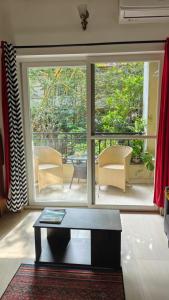 ein Wohnzimmer mit großem Fenster und Tisch in der Unterkunft MalangFehmi Goa Escape in Arambol