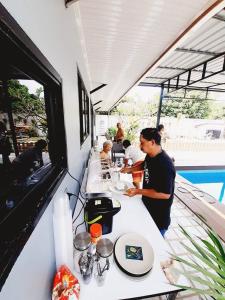 een man zit aan een tafel in een restaurant bij สกลนครพูลวิลล่า in Sakon Nakhon