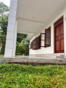 a building with brown doors and a grass yard at Riverside Serenity in Talpe
