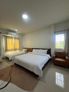 ein großes Schlafzimmer mit zwei Betten und einem Sessel in der Unterkunft บ้านใจฟู URBAN HOMe in Mukdahan