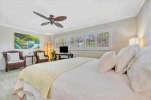 a bedroom with a white bed with a ceiling fan at Siesta Key Beach Waterfront Home with Kayaks and Bikes in Siesta Key +27 photos