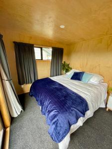 a bedroom with a large bed with a blue blanket at Watkins Tiny Retreat in Rangiora