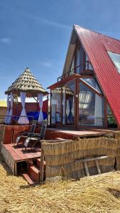 een huisje met twee stoelen, een parasol en hooi bij Titicaca Alpina HARMONY lodge in Puno