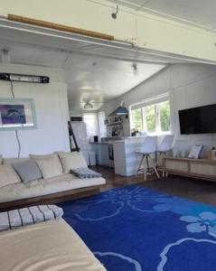 a living room with a couch and a blue rug at Pipi Palace in Papamoa +13 photos