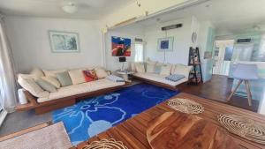 a living room with two couches and a blue rug at Pipi Palace in Papamoa