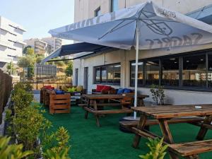 een patio met houten banken en een parasol bij Hotel ibis Leiria Fatima in Leiria