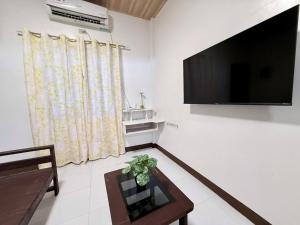 ein Wohnzimmer mit Fernseher und Tisch in der Unterkunft Harry's Near the Beach Siargao in General Luna