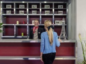 een vrouw aan een balie met een man bij Mercure Cergy Pontoise Centre in Cergy