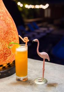 a glass of orange juice with a fake flamingo on a table at Brother Hotel & Travel in Cat Ba