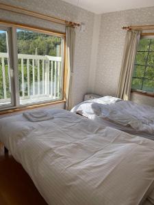 una camera da letto con due letti e due finestre di aomame villa lake toya a Lago Toya