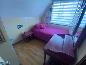 una piccola camera con letto rosa e tavolo di Refugio urbano a Villarrica 1 altra foto