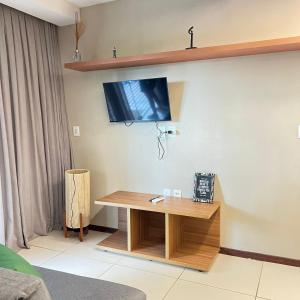 ein Wohnzimmer mit einem Tisch und einem Fernseher an der Wand in der Unterkunft Studio em Villas do Pratagy in Maceió