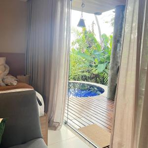Schlafzimmer mit einer Glasschiebetür zur Terrasse in der Unterkunft Studio em Villas do Pratagy in Maceió