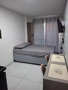 een slaapkamer met een bed, een tafel en een tv bij Eco mirage Residence in Porto De Galinhas