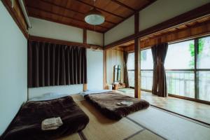 a bedroom with a large bed in a room with windows at Hostel&Bar CAMOSIBA in Yokote