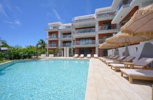 a swimming pool with chairs and umbrellas next to a building at Residence ORYAM in Trou aux Biches